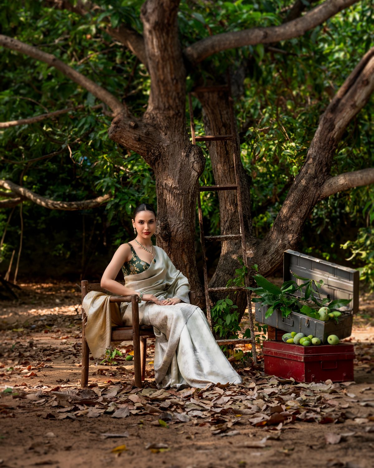 Model in an ivory tussar silk saree seated beneath a mango tree